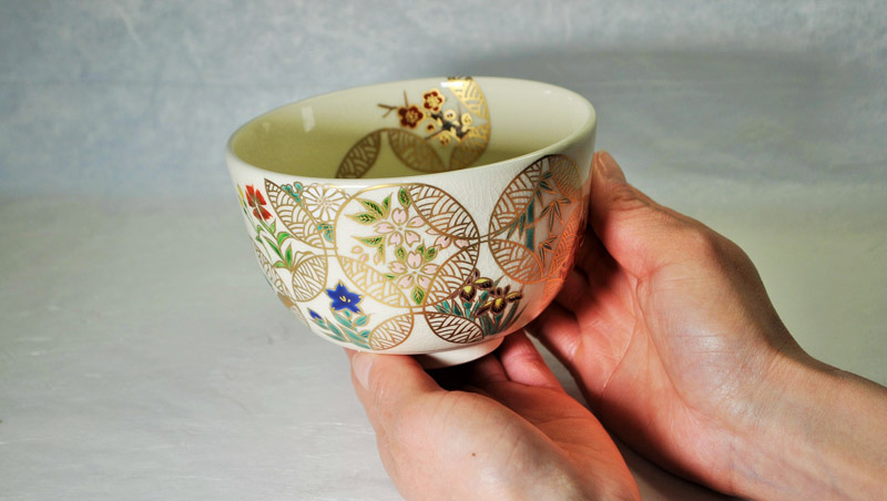 抹茶碗 四季七宝つなぎを両手に持つ女性の画像